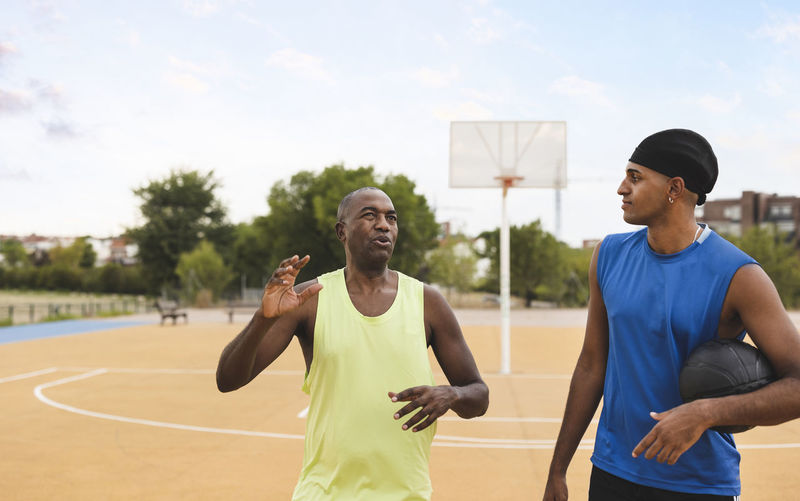 Mature man talking with son at basketball court