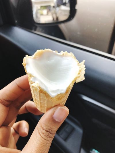 Midsection of person holding ice cream cone in car