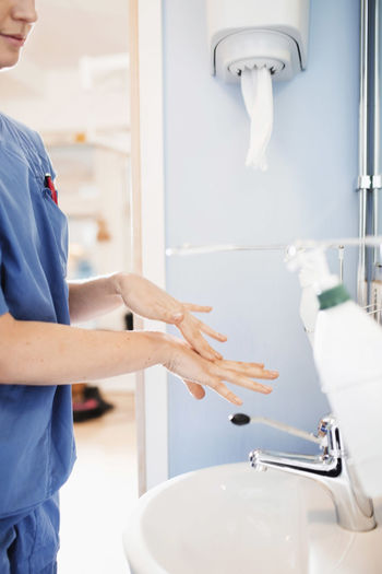 Side view of young nurse washing hands in hospital bathroom