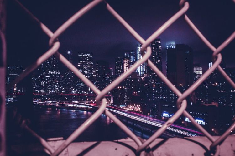 Close-up of chainlink fence in city at night