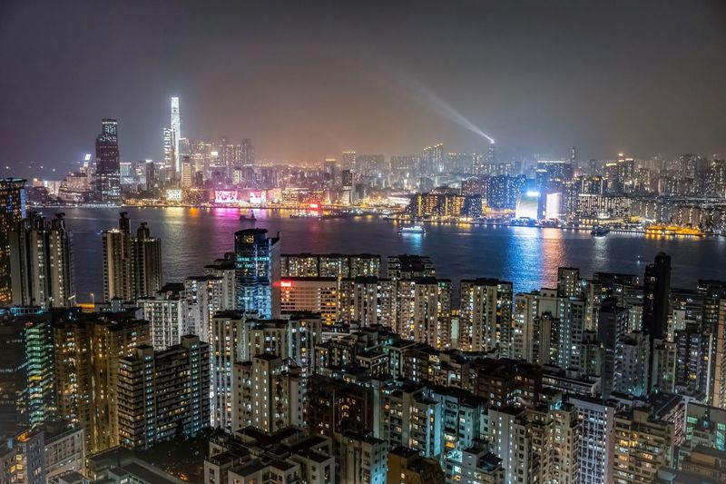 Illuminated modern buildings in city against sky at night