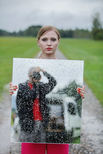 Portrait of young woman standing on puddle