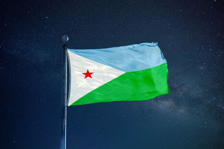 Low angle view of djibouti flag against star field sky