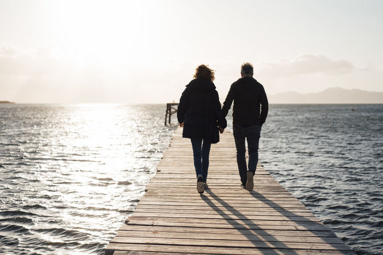 Couple holding hands walking together on jetty