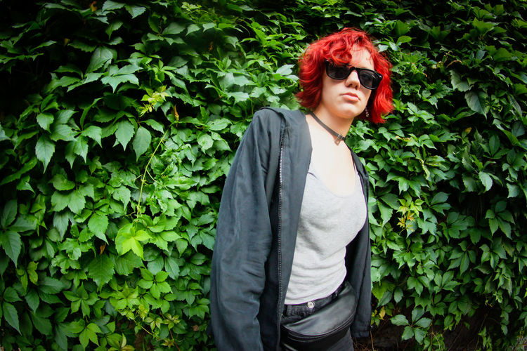 Young woman wearing sunglasses standing by plants