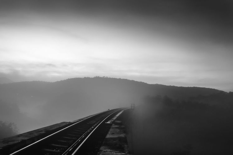 Railroad tracks by mountain against sky