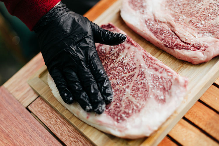 Human hand seasoning a wagyu kobe steak with salt