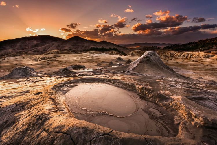 Scenic view of berca mud volcanoes against sky during sunset