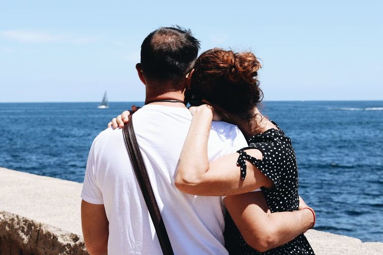 Rear view of couple hugging against sea