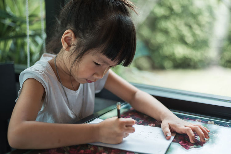 Close-up of girl studying at table