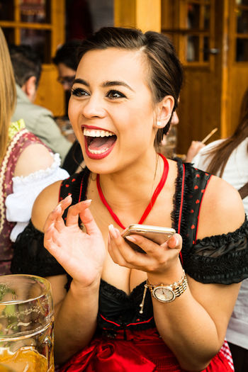 Happy beautiful woman holding smart phone at oktoberfest