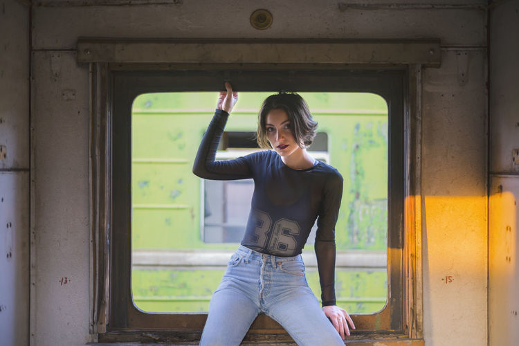 Portrait of beautiful woman sitting on window in train