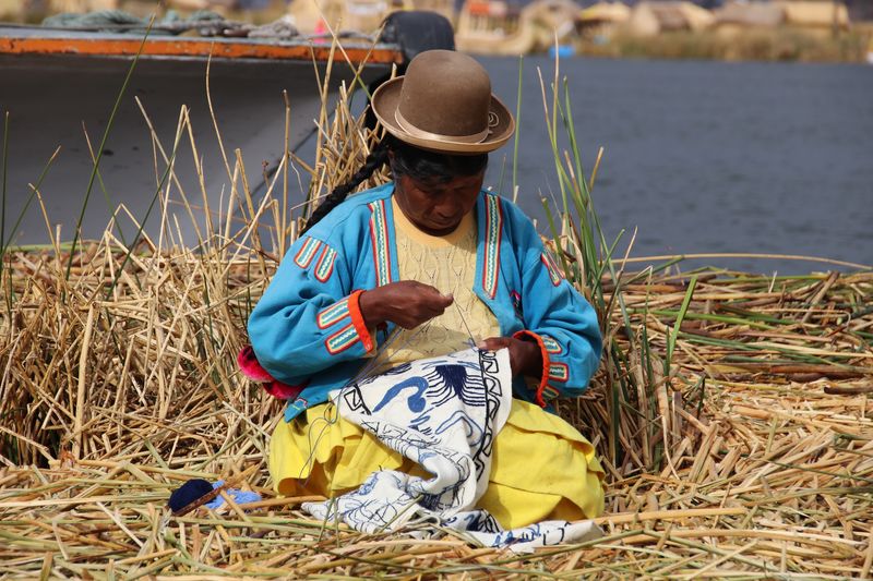 Woman sewing textile while sitting on straw