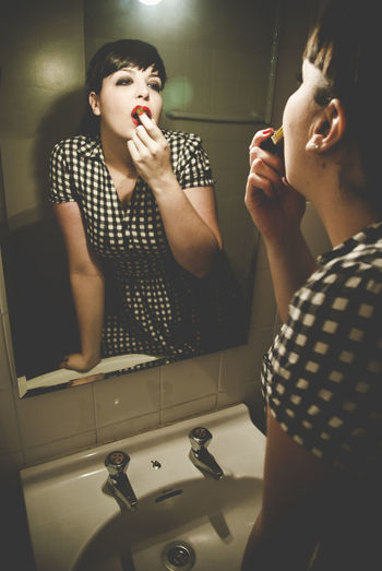 Woman applying lipstick in bathroom
