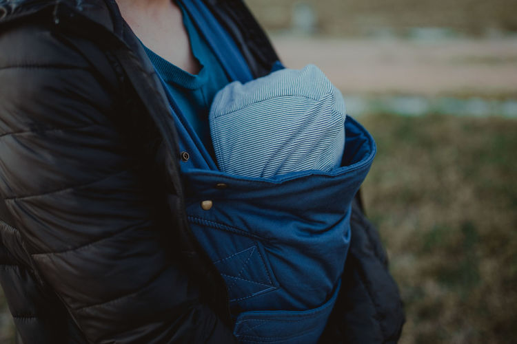 Rear view of woman with baby in carrier in park
