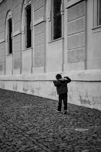 Full length rear view of boy walking on street