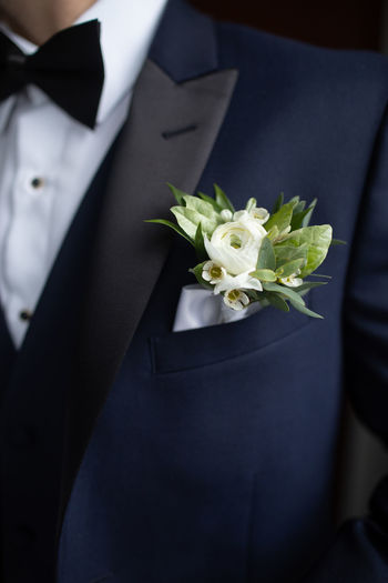 Midsection of bridegroom holding bouquet