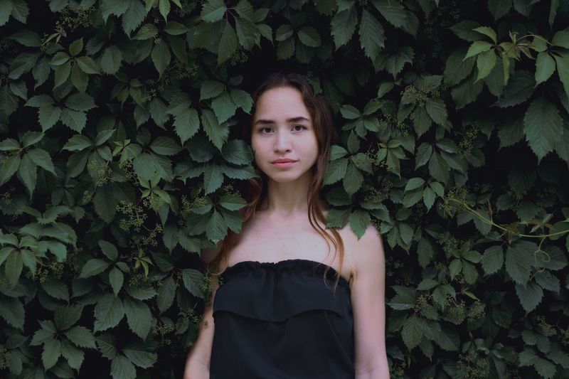 Portrait of a beautiful young woman standing against plants