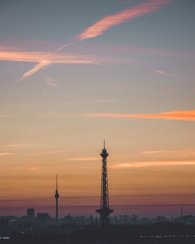 Distant view of tower and cityscape against sky during sunset