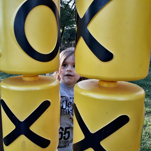 Girl standing by yellow play equipment