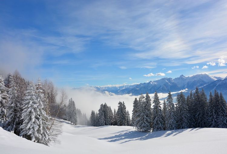 Scenic view of snow covered mountains against sky and a long blanket of snow.