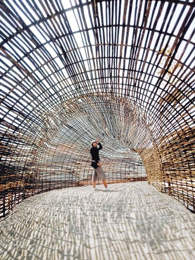Full length of woman standing against wooden tunnel
