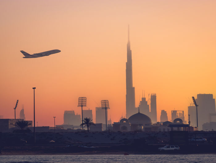 Emirates airlines flying in the sky of dubai over the burj khalifa at sunset
