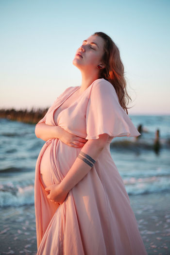 BEAUTIFUL YOUNG WOMAN LOOKING AT SEA