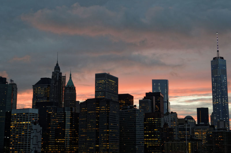 Buildings in city against cloudy sky during sunset