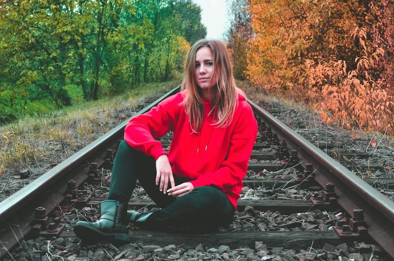 Portrait of young woman on railroad track by trees
