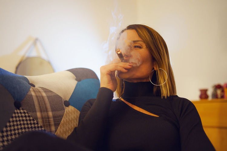 Woman smoking cigar while relaxing at home