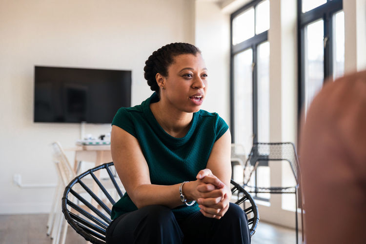 Young businesswoman sitting with hands clasped in meeting at office
