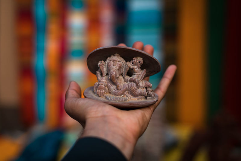 Close-up of cropped hand holding ganesha figurine