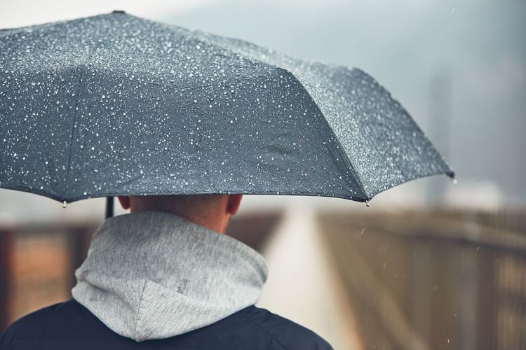 Close-up of man holding umbrella during rainy season