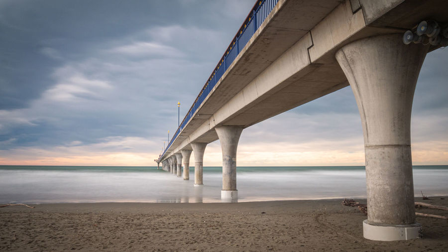Massive concrete pier leading to horizon surrounded by ocean. new brighton,christchurch, new zealand