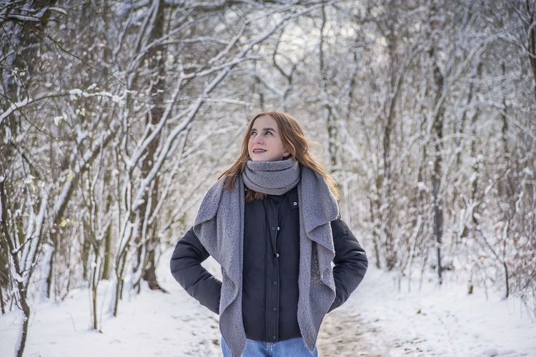 Girl standing in forest during winter