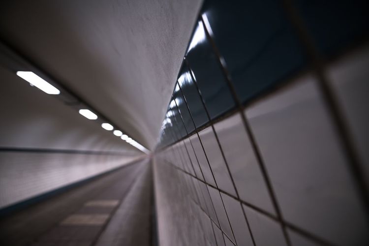 Close-up of tiled wall in illuminated tunnel