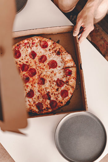 High angle view of hand holding pizza on table