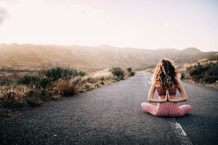 Rear view of woman practicing yoga on road