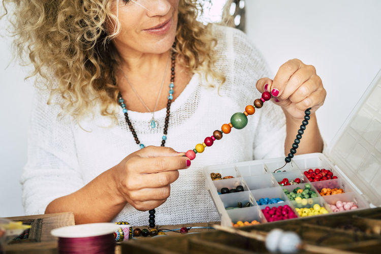 Midsection of woman holding multi colored beads at home