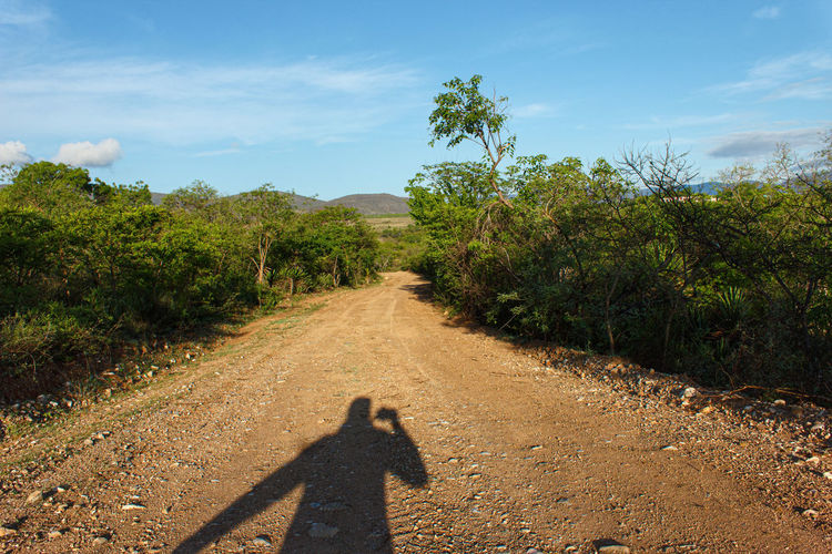 Shadow of man on dirt road