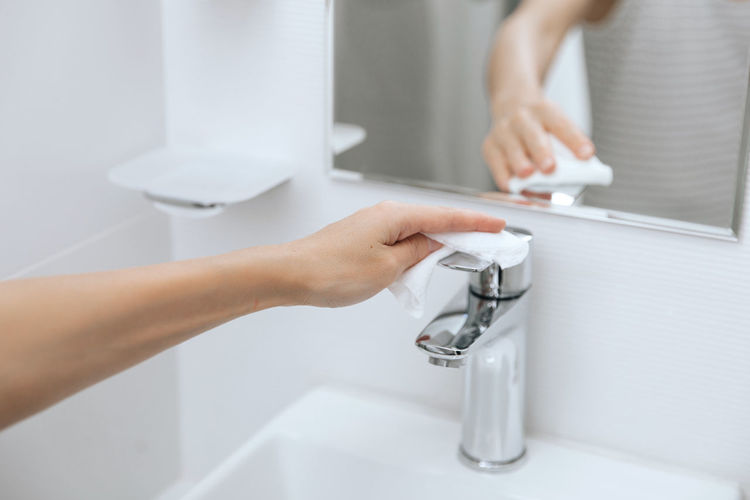 Cleaning the sink faucet with a microfiber cloth. sanitize surfaces prevention in hospital