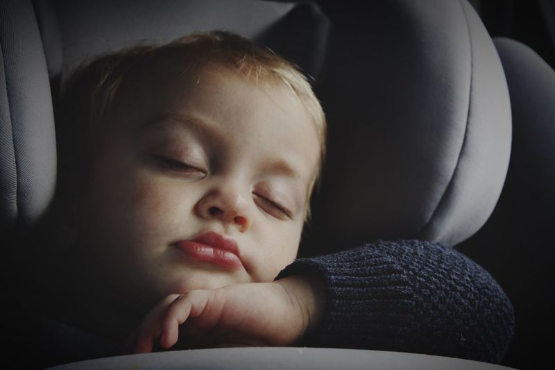 Close-up of cute baby boy sleeping on car seat