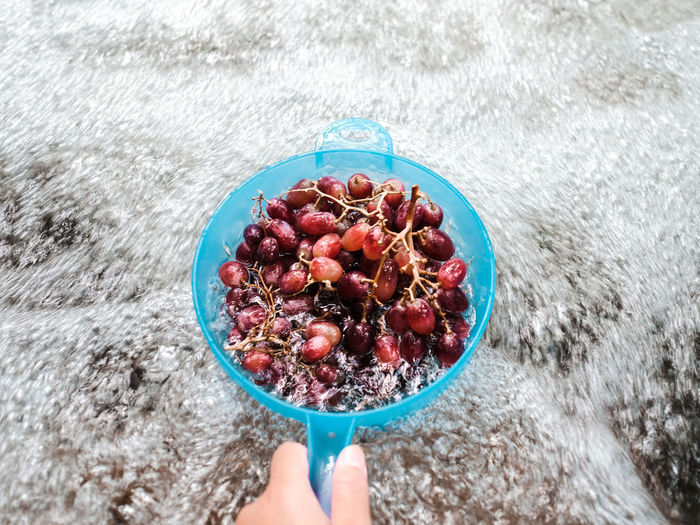 High angle view of grapes in a blue strainer in a stream