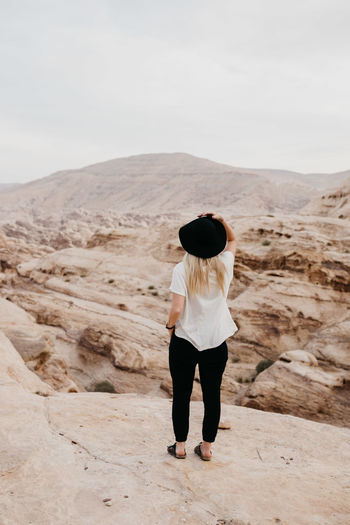 Rear view of young woman standing at desert against sky