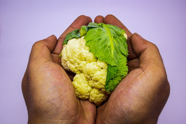 Close-up of hand holding strawberry over white background