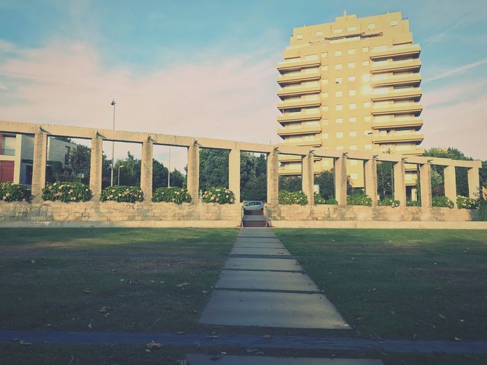 Footpath by building against sky in city