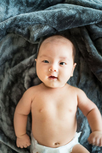 Directly above portrait of shirtless baby lying on blanket