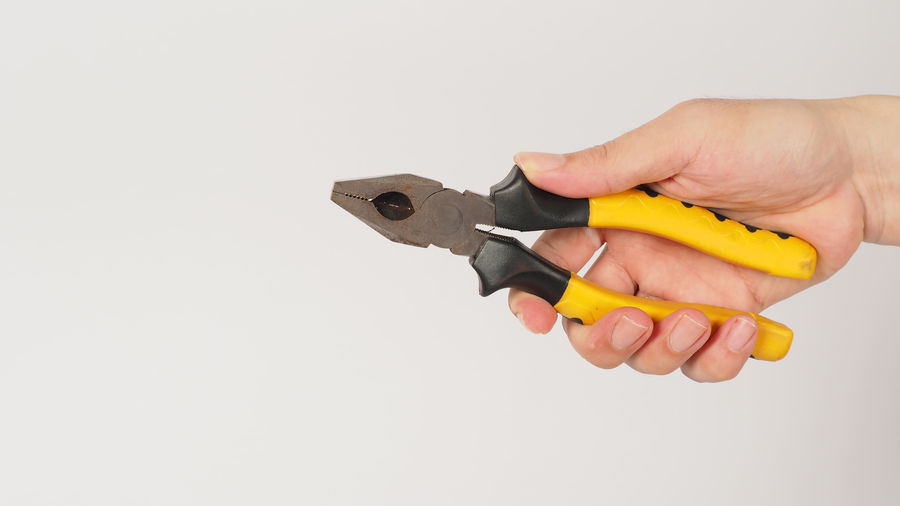 Close-up of hand holding hammer against white background