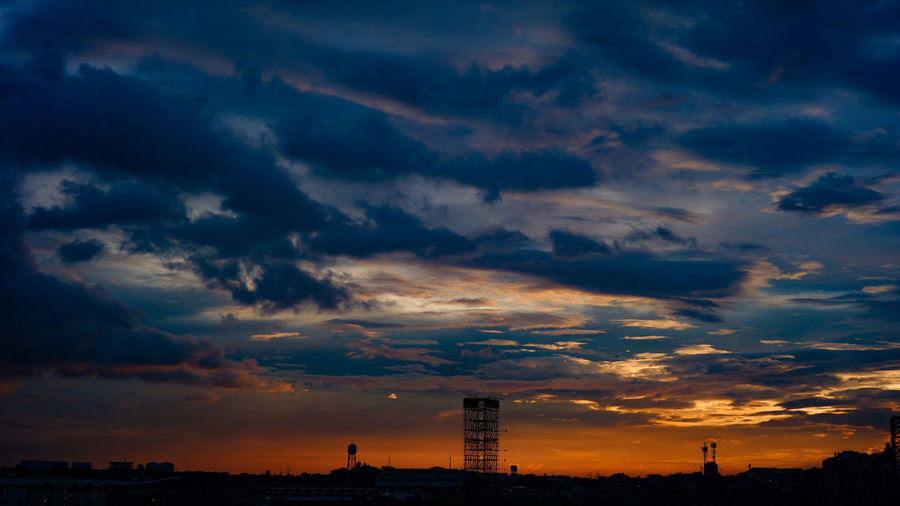 Low angle view of silhouette buildings against dramatic sky